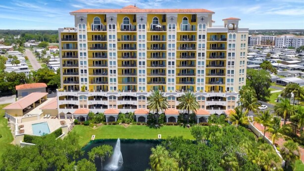 A multi-story hotel with balconies, a swimming pool, and a fountain.