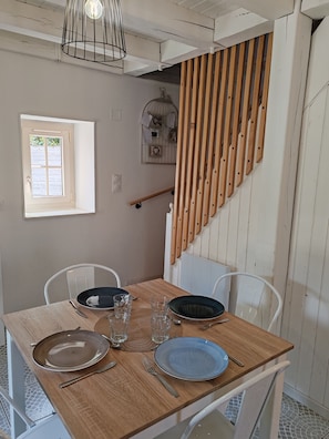 A dining area with a wooden table set for two, two chairs, and a window with a view. - Cottage in Sully sur Loire (Sully-sur-Loire)