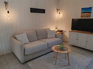 Een woonkamer met een bank, een salontafel, een televisie en wandlampen.