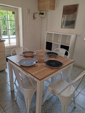 Ein Essbereich mit einem Holztisch, weißen Stühlen und einem weißen Schrank mit Regalen.