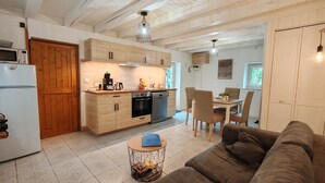 Una cocina moderna con armarios de madera, un comedor con mesa y sillas, y una sala de estar con sofá.