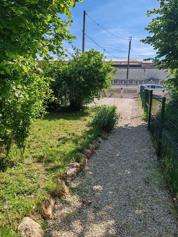 A gravel pathway leading to a building with a fence and a parked car. - Cottage in Sully sur Loire (Sully-sur-Loire)