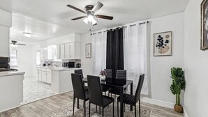 A modern kitchen with white cabinets, a dining area with black chairs, and a ceiling fan. - Serene 3BR Luxe Easy Access to NRG & Galleria (Houston)