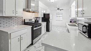 A modern kitchen with white cabinetry, a black stove, a refrigerator, and a microwave. - Serene 3BR Luxe Easy Access to NRG & Galleria (Houston)