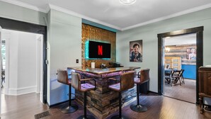 Zona de bar amb logotip de Netflix, taulell de bar de fusta i quatre tamborets.