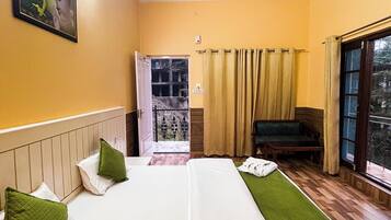 Habitación de hotel con dos camas, un ventilador de techo, un cuadro en la pared, una ventana con cortinas y vistas al exterior.