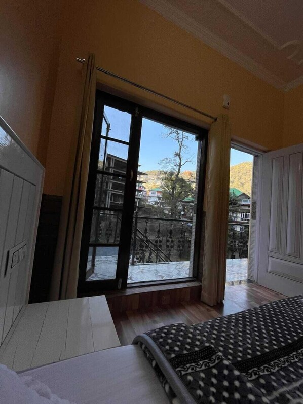 Une chambre avec une grande fenêtre, un lit et une armoire.