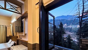 Camera d'albergo con una grande finestra, un letto, una televisione e un bagno.