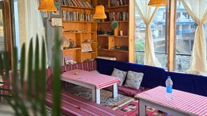 Un angolo accogliente per la lettura con una libreria, un tavolino con tovaglia a scacchi e una panca imbottita blu.