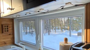 A kitchen with a large window, a sink, a toaster, and a towel on the counter.