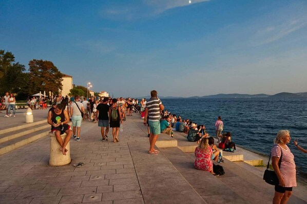 Un paseo público con gente sentada y caminando a lo largo del paseo marítimo.
