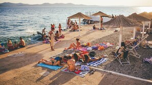 A beach with people sunbathing, umbrellas, and a view of the sea. - Charming 2-bedroom apartment with AC, WiFi in fantastic centre of the Zadar (Zadar)