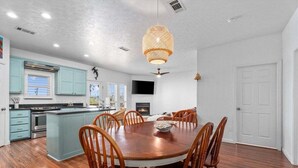 A modern kitchen with a central island, wooden chairs, and a dining table. - Canalfront | Hot Tub | Boat Slip | Sleeps 10 (Crystal Beach)