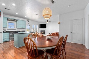 A modern kitchen with a central island, wooden chairs, and a dining table.