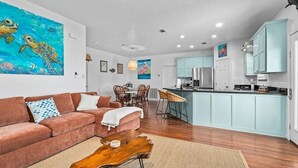 A modern living room with a sofa, coffee table, and artwork on the wall. - Canalfront | Hot Tub | Boat Slip | Sleeps 10 (Crystal Beach)