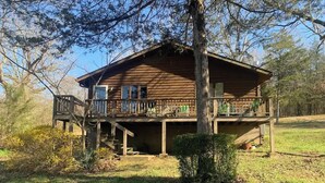 Une cabane en bois dotée d’une terrasse et d’un porche abrité.
