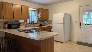 Une cuisine avec des meubles de rangement en bois, un réfrigérateur blanc, un four à micro-ondes et une cuisinière à gaz.