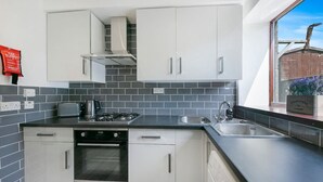 Eine moderne Küche mit weißen Schränken, einem Gasherd und einem eingebauten Backofen.