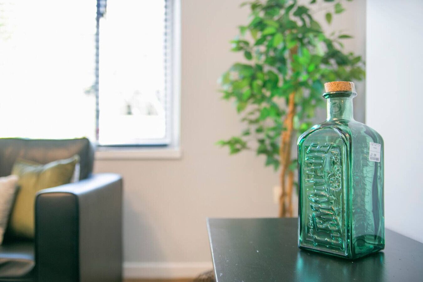 A green glass bottle with a cork stopper on a dark surface.