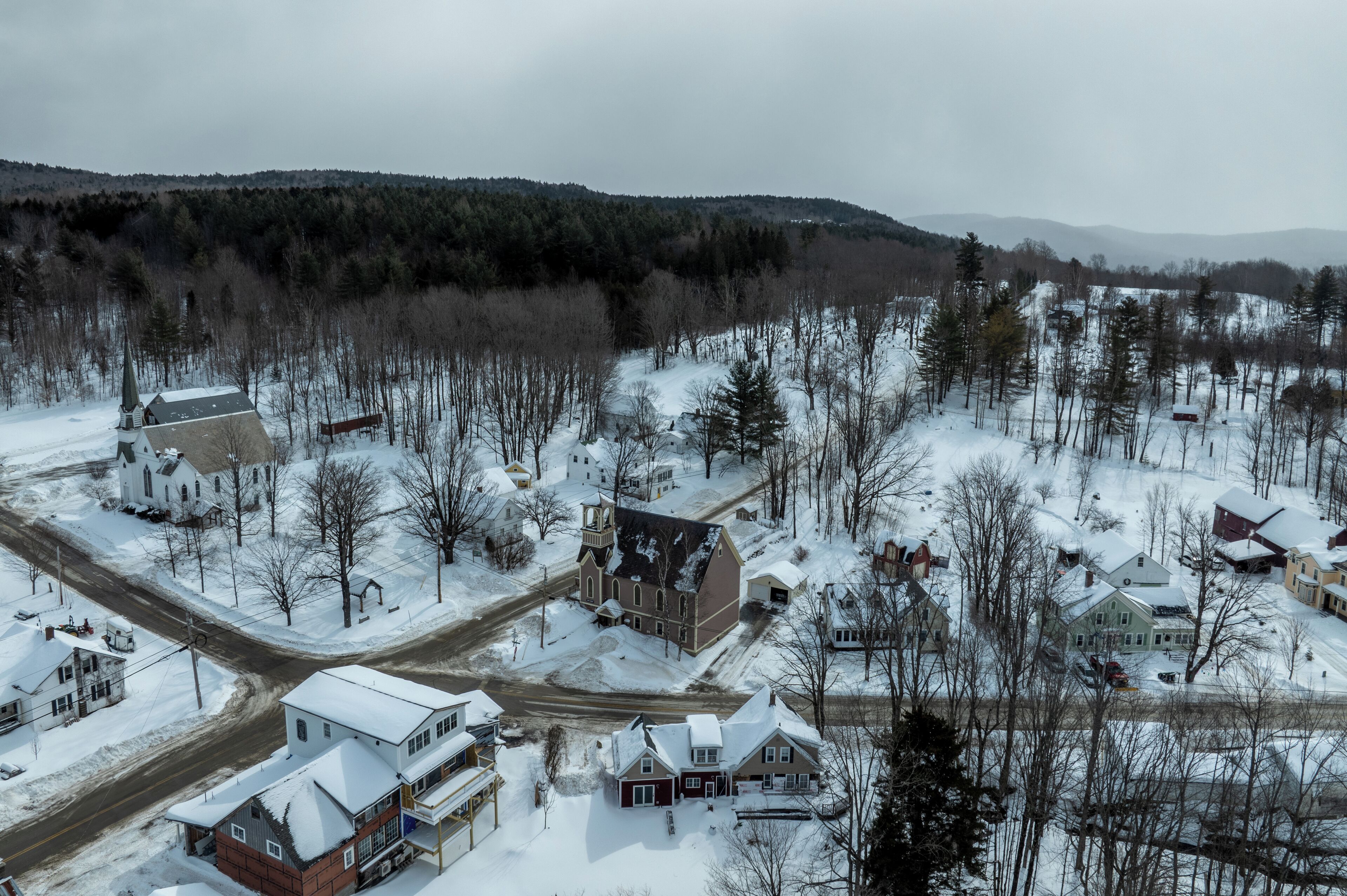 Et snedækket boligområde med huse, en kirke og en vej.