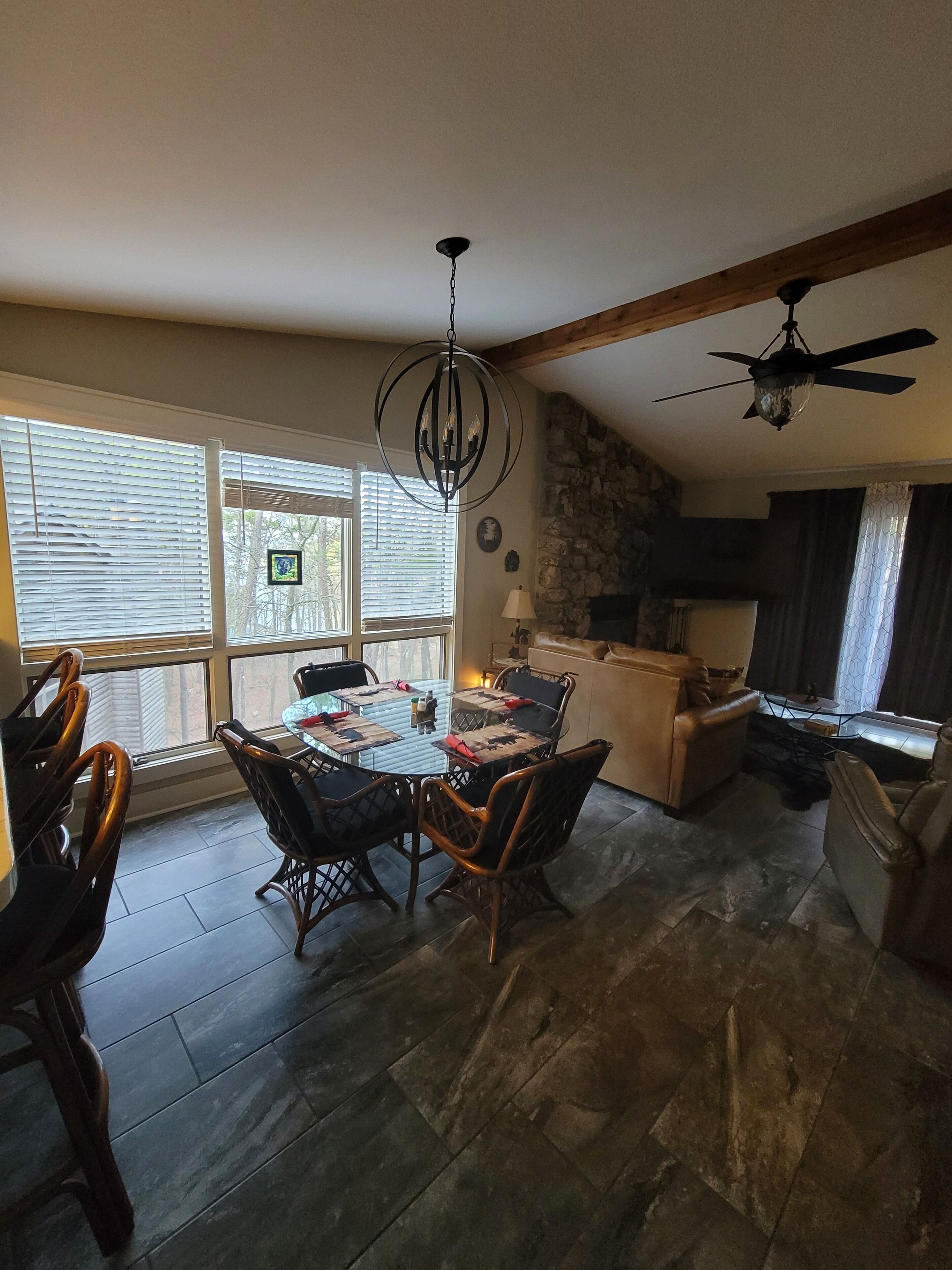 A dining area with a round table and chairs, a chandelier, and a stone wall.