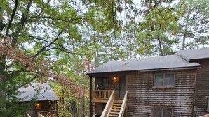 A wooden cabin with a wooden deck and stairs leading to the main building. - The Bear Den  (Mount Ida)