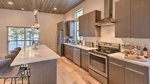 Una cocina moderna con una isla grande, electrodomésticos de acero inoxidable y techo de madera.