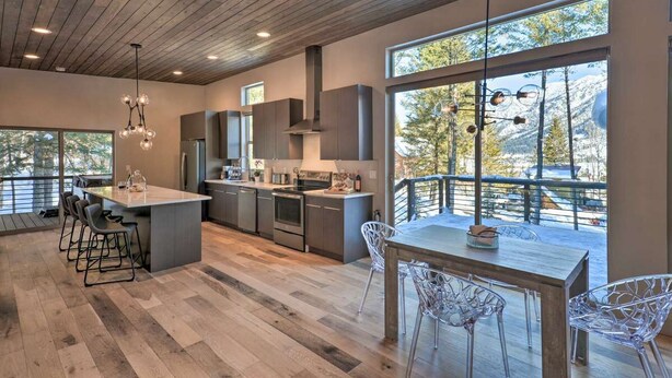 Una cocina moderna con una isla central, asientos tipo barra y amplios ventanales que ofrecen vistas al exterior.