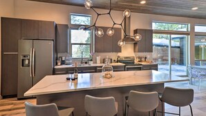 Una cocina moderna con una isla grande, electrodomésticos de acero inoxidable y una lámpara colgante original.