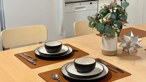 A modern kitchen with a dining table set for two, a refrigerator, a microwave, and a sink. - Levida Living - Cozy 2 Bedroom Suite at the Heart of Langley (Langley)