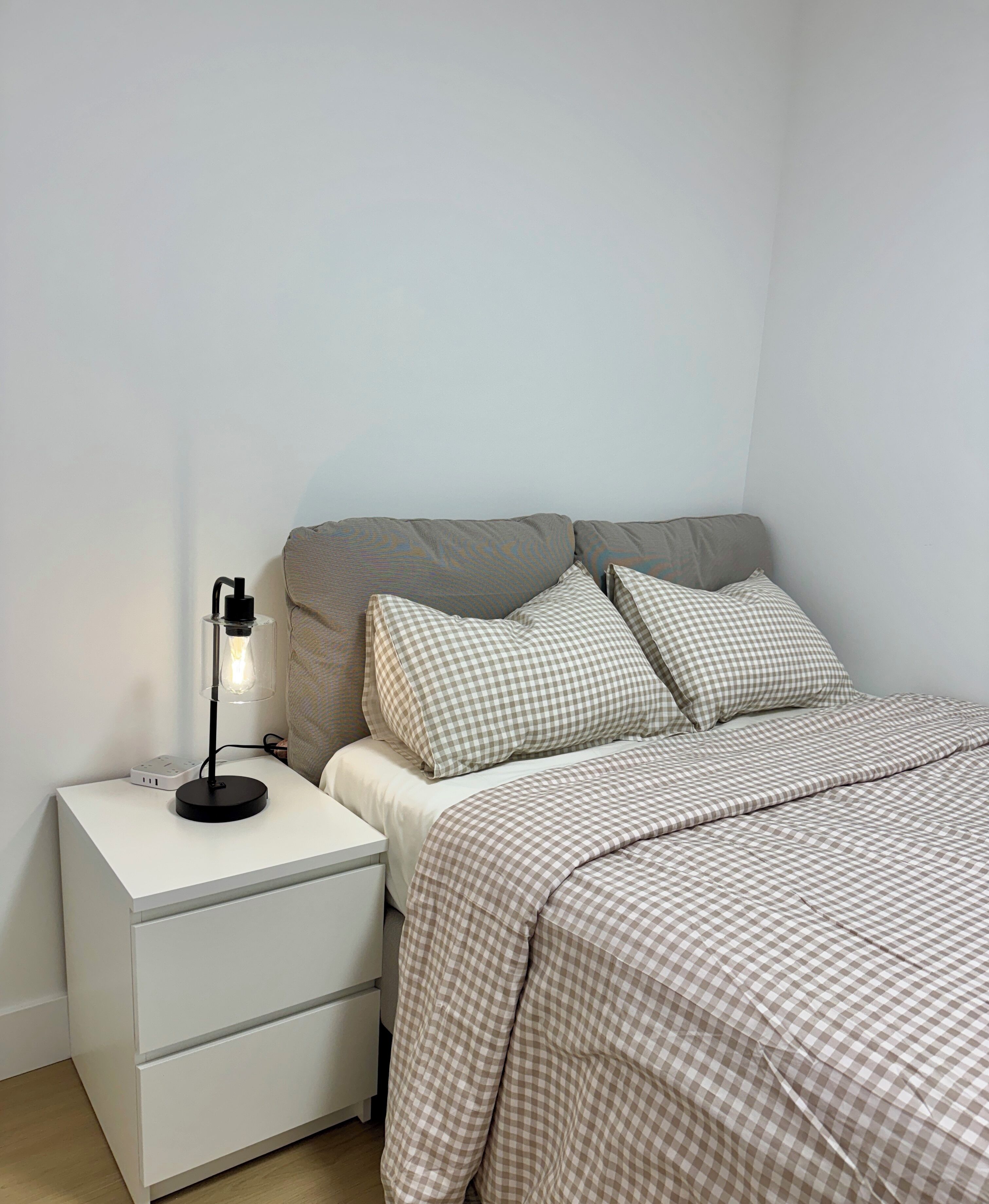 Ein ordentlich eingerichtetes Schlafzimmer mit Bett, Kissen, Nachttisch und Lampe.