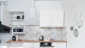 Eine moderne Küche mit weißen Schränken, einer Mikrowelle, einer Kaffeemaschine und einem Geschirrspüler.