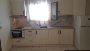 A kitchen with a built-in oven, a sink, and cabinets. - Lefkis apartments & studios (West Mani)