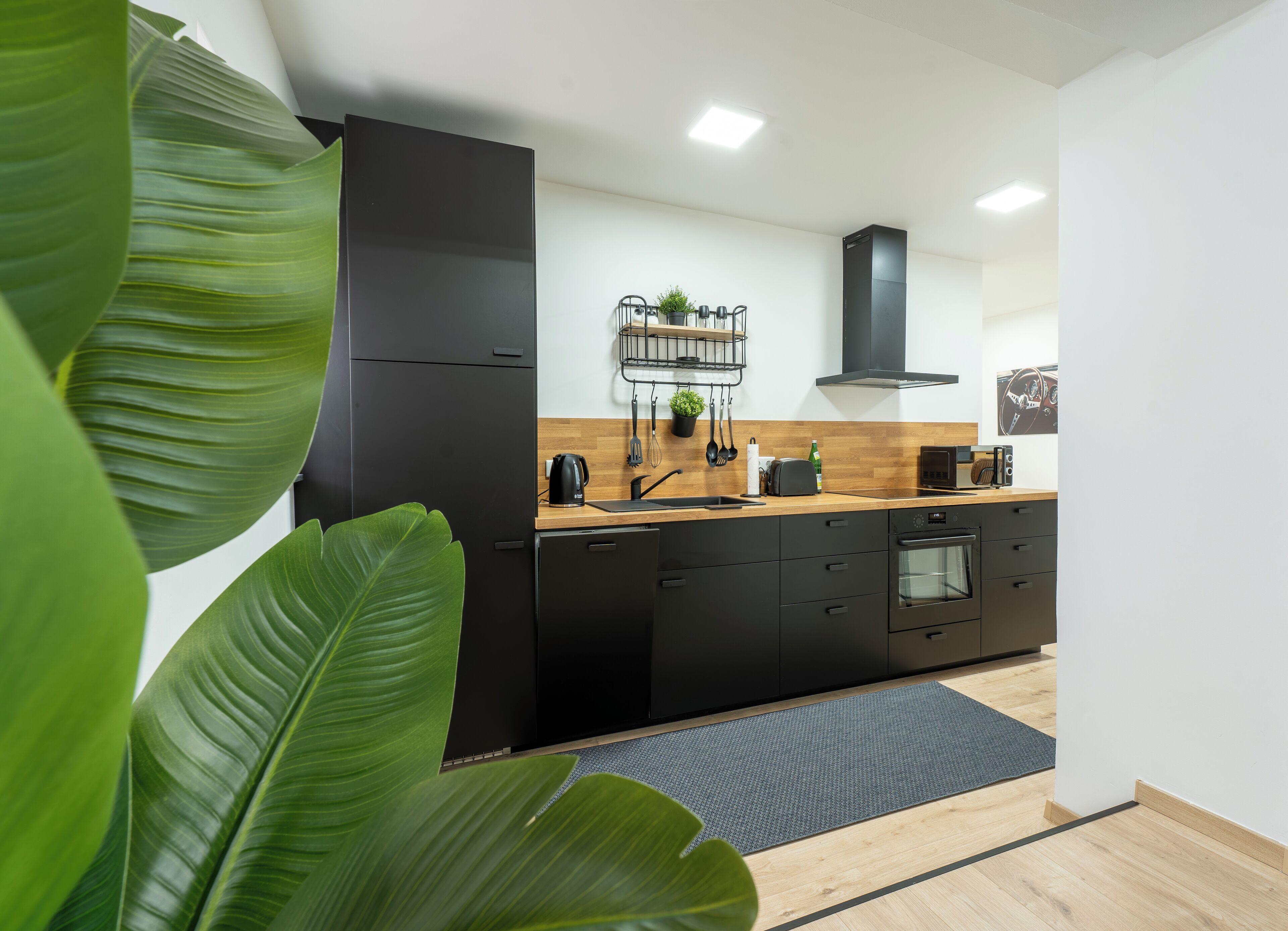 Eine moderne Küche mit schwarzen Geräten, Holz Arbeitsplatten und einer schwarzen Dunstabzugshaube.