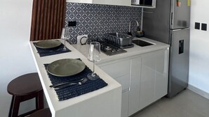 Cozinha moderna com armários brancos, geladeira de aço inoxidável, micro-ondas e fogão a gás.