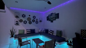 Uma sala de estar moderna com mesa de bilhar, área de estar, ventilador de teto e arte decorativa na parede.