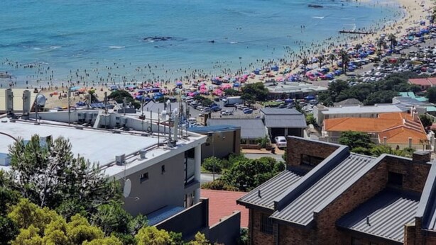A coastal town with a beach, buildings, and a clear view of the sea. - Cloud 9 Room 6 King Bed & Stunning Views (Cape Town)