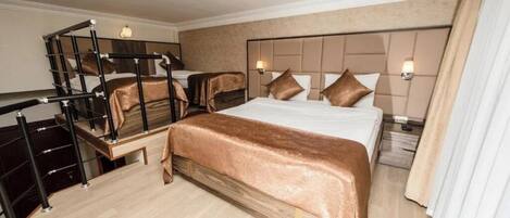 A hotel room with a large bed, a desk with a chair, a small table, and a staircase.