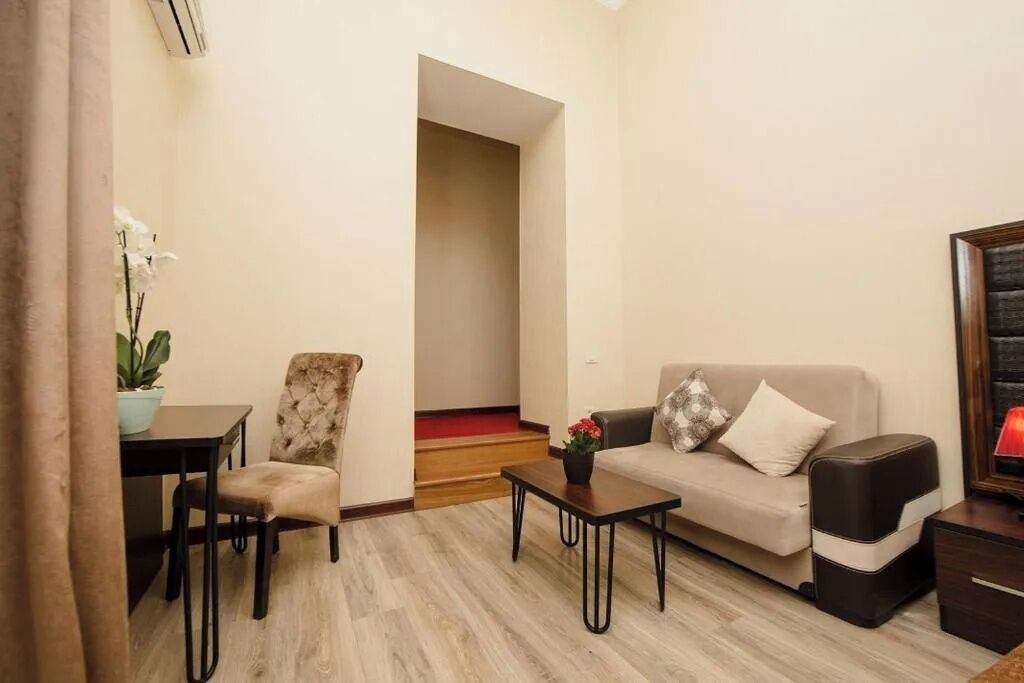 Una sala de estar con un sofá, un sillón, una mesa de centro y una mesita con una planta.
