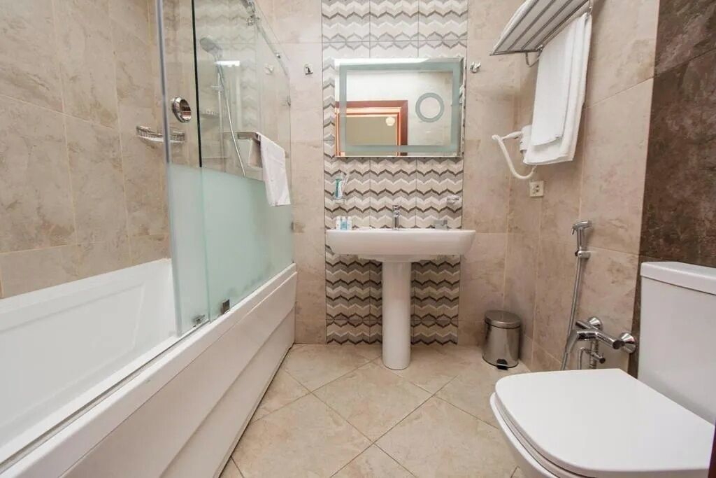 Ein Badezimmer mit einer Duschkabine, einem Standwaschbecken und einer Toilette.
