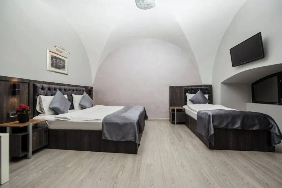 Ein modernes Schlafzimmer mit zwei Betten, einem Flachbildfernseher und einem gerahmten Bild an der Wand.