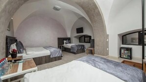 Een moderne hotelkamer met twee bedden, een klein bureau, een televisie en een minibar.