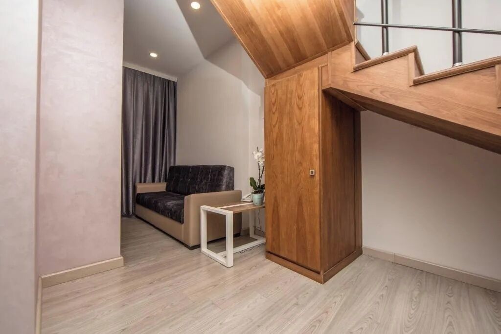 A modern living room with a sofa, a small white table, and a wooden cabinet.