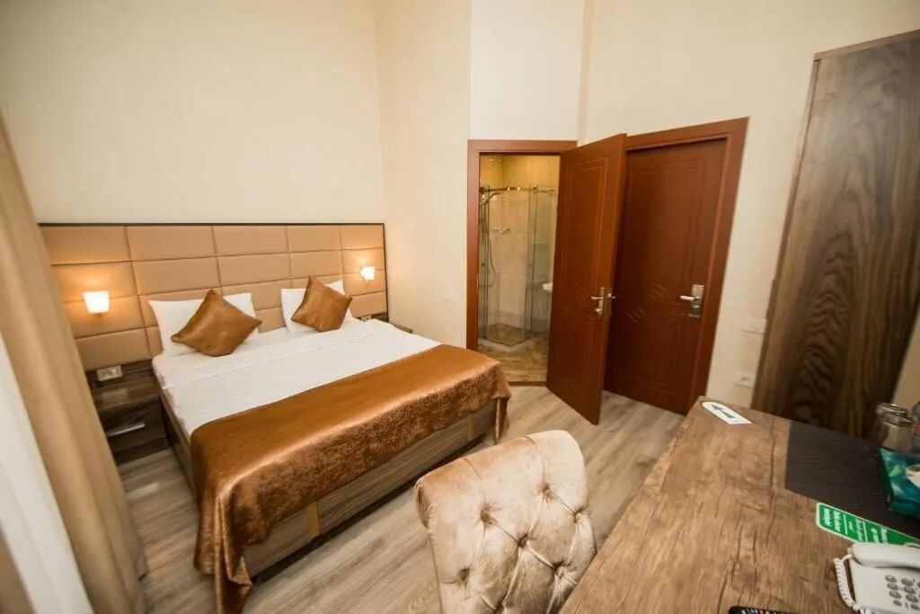 Een hotelkamer met een bed, nachtkastje en een douchehoek.
