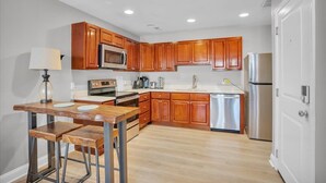 A modern kitchen with wooden cabinets, stainless steel appliances, and a wooden dining table with stools. - Spacious 3-bedroom apartment with AC, WiFi near Temple in marvelous Philadelphia (Philadelphia)