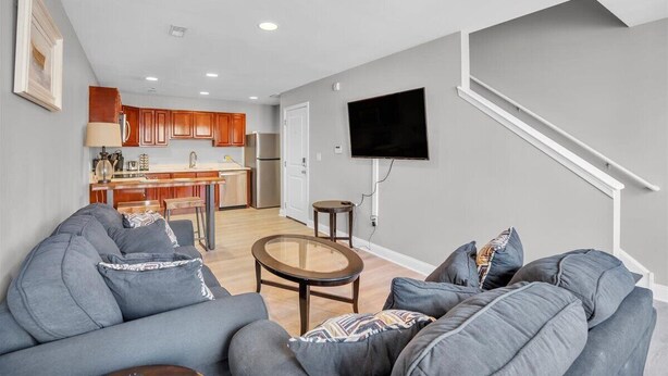 A modern living room with a grey sofa, a small round table, and a flat-screen TV mounted on the wall. - Spacious 3-bedroom apartment with AC, WiFi near Temple in marvelous Philadelphia (Philadelphia)