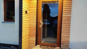 A modern entrance with a wooden door and a small set of stone steps leading up to it. - Vacation home with panoramic sauna, free e-bike rental & space for 6 people! (Sankt Gertraud)