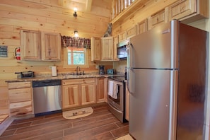 Una cocina de estilo cabaña de madera con un refrigerador, lavavajillas y horno de acero inoxidable.