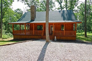Une cabane en bois avec un porche, une cheminée et une allée gravillonnée.
