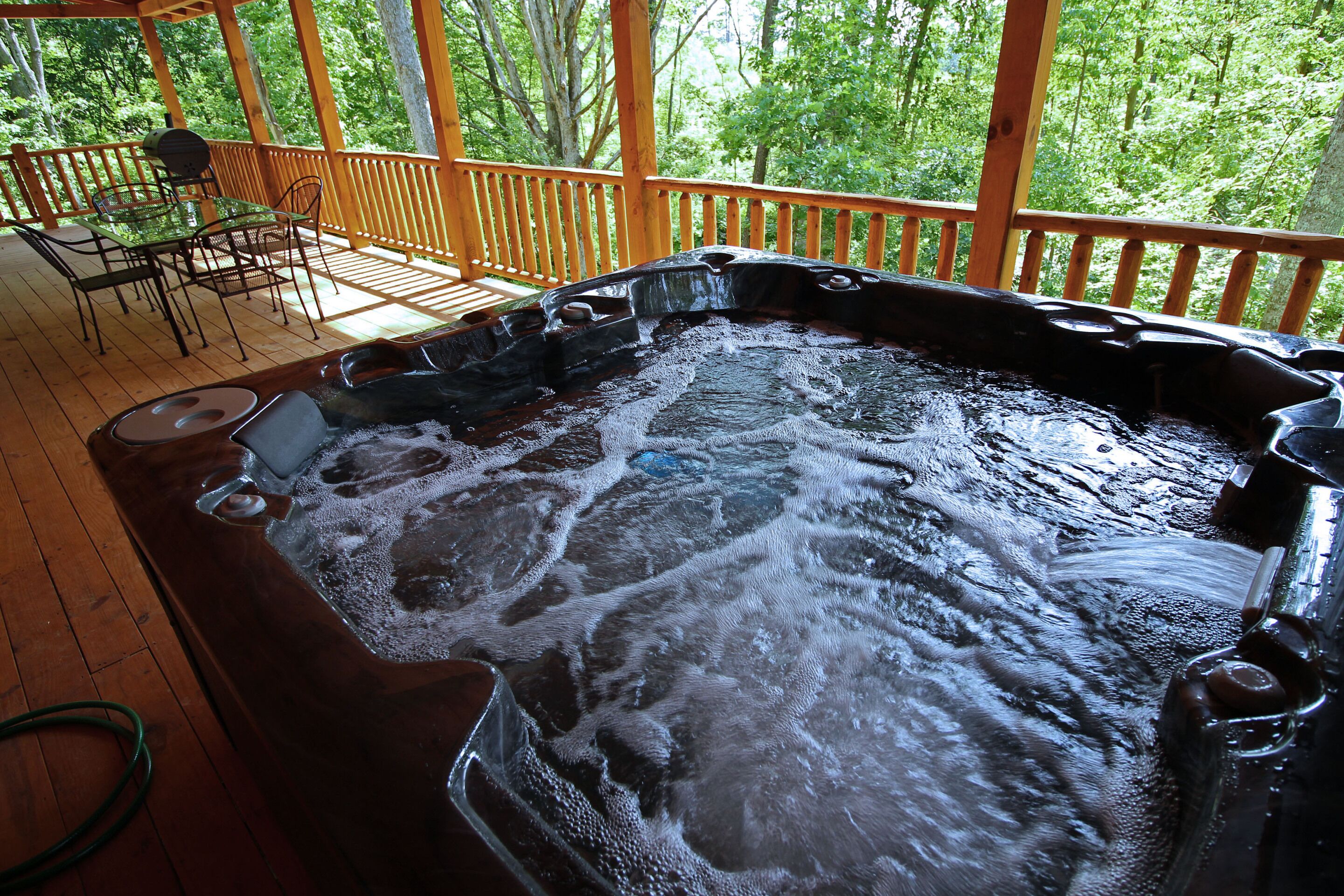 A hot tub with a wooden deck and outdoor furniture.